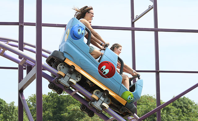 blue rollercoaster carriage on a purple track descending at speed